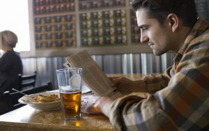 Man dining alone reading newspaper 