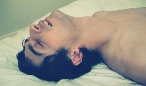 Man laying on bed climaxing